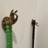 Brass mudra hand hook wall-mounted as key hanger and jewelry holder, shown with beads and strap