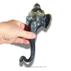 Decorative wall hook shaped like an elephant head with a hand holding it, on a white background.