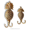 Two gold pineapple-shaped hooks on a white background