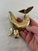 gold brass whale coat hook in hand in front of a white background