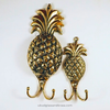 Decorative pineapple-shaped gold hooks on a white background