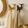 Ai generated image of the gold and antique brass whale towel hangers in a nautical boho bathroom with towels
