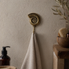 Brass ammonite fossil wall hook used as towel hanger in coastal bathroom decor