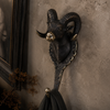 Antique brass ram wall hook mounted on a dark wall with black coat hanging — solid brass gothic coat hook for entryway handmade in Ubud Bali