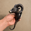 Hand holding antique brass ram wall hook showing detailed sculpted ram face with curved horns — solid brass decorative wall hook handmade in Bali