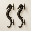 Matched pair of antique bronze seahorse door pulls on cream background