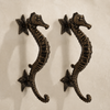 Antique bronze seahorse door pull set on cream background, vintage double door hardware