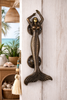Antique brass mermaid door handle mounted on front door for vintage nautical entry hardware.