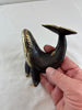 gold brass whale coat hook in hand in front of a white background