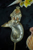 Decorative mermaid tail on a stick with shells and flowers in the background
