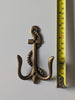 Brass anchor wall hook next to measuring tape showing size for nautical bathroom decor