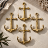 Brass anchor wall hook set mounted in a cluster on a textured cream wall near coral decor, maritime coastal wall hook display