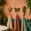 Brass ocean animal wall hooks mounted on a terracotta wall with teal tile, coastal nautical bathroom hook set.