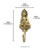 Gold brass sitting buddha wall hook mounted on warm neutral wall in styled meditation corner with mala beads, crystal cluster, books and tropical plant showing spiritual boho home decor lifestyle styling. Handcrafted sitting buddha coat hook for yoga room decor, meditation space decor, zen home decor, buddhist decor and housewarming gift. Made by professional artisans in Bali