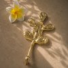 Brass cactus wall hook styled with a tropical frangipani flower on a neutral surface, showcasing handmade boho desert home decor.