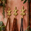 Set of 3 handmade brass cactus wall hooks mounted on a terracotta wall, holding a leather bag and scarves as boho entryway coat hooks.