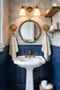 Brass clam shell wall hook in coastal bathroom near sink and mirror.