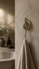 Brass conch shell wall hook used as towel hanger in warm coastal bathroom decor