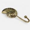 Brass conch shell wall hook held in hand showing size and polished brass finish