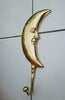 Original product photo of gold brass crescent moon wall hook with face detail mounted on a light tiled wall