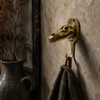 Close-up of brass crocodile alligator skull wall hook on a dark textured wall with bag hanging — man cave gothic skull wall hook handmade in Bali