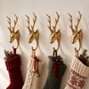 Four brass deer stocking hangers holding red, cream, green and Fair Isle knit stockings in a festive Christmas mantel display. A stocking holder set for the whole family that doubles as hunting cabin decor all year, and a thoughtful gift for hunter families, handmade in Bali.