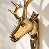 Close-up of the brass deer wall hook showing the hand-cast detail of the stag's face, ears and branching antlers in polished gold. Handmade antler wall decor and animal wall hook from Ubud, Bali.