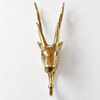 Front view of the brass deer wall hook on a plain light wall, showing the symmetrical tall antlers, the stag's face and the hook with ball tip below. A handmade coat hook and Christmas gift for deer lovers, hand-cast in Bali.