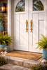 Two brass dolphin door handles installed on a double front door, nautical coastal entry door pull set