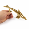 Shiny gold brass dolphin door handle held in hand for scale, coastal entry door pull hardware