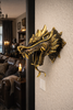 Brass dragon head wall mount installed on wall in moody gothic dark academia interior.