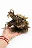 Hand holding brass dragon head wall mount to show scale and weight