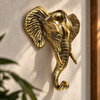 Brass elephant wall hook in gold finish mounted on a textured wall near a plant, boho home decor accent