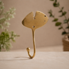 Back view of gold brass fan leaf wall hook on warm neutral background showing single mounting hole and sturdy solid brass construction for easy wall installation. Handcrafted leaf shaped plant hanger hook, towel hook and coat hook for boho home decor, housewarming gift and nature-inspired bathroom and entryway wall decor