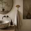 Gold brass fan leaf wall hook mounted on neutral bathroom wall beside round mirror and stone basin sink with white towel hanging showing minimal boho bathroom lifestyle styling. Handcrafted leaf shaped towel hook, shower hook and plant hanger hook for boho home decor, housewarming gift and nature-inspired bathroom wall decor. Available in gold and dark antique finish