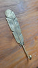 Back view of brass feather wall hook on wooden surface