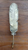 Front view of brass feather wall hook on wooden surface