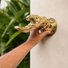 Hand installing a solid brass fingering hand wall hook on a wall, showing the polished brass finish and mounting detail.