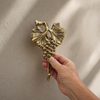 Brass grape wall hook mounted on wall holding towel, vintage kitchen towel hook, farmhouse and wine decor style