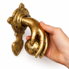 Hand holding brass fist and ball door knocker to show size and detail, solid brass door hardware statement piece