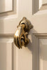 Side view of brass hand door knocker mounted on door, fist and ball design, decorative exterior door hardware