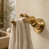 Brass fingering hand wall hook mounted on a tan wall holding a towel, novelty bathroom hook and funny statement decor.