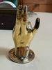 Brass hand sculpture hook standing on base, novelty gesture decor, polished finish with contrasting fingertip detail