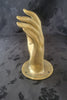 Side angle of a gold-finish brass hand wall sculpture with textured base.