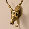 Close-up of solid brass impala skull wall hook on a dark moody background showing detailed sculpted skull face curved horns and antique brass texture — gothic skull wall hook handmade in Bali