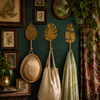 Brass leaf wall hook set mounted on a dark eclectic gallery wall with framed botanical art and hanging bags.