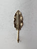 Brass leaf wall hook in antique finish mounted on textured wall