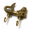 Brass mermaid double wall hook on dark grey background showing intricate sculptural mermaid detail, scaled tail, flowing hair and aged antique brass patina finish. Handcrafted coastal nautical decorative coat hook and towel hook for beach house decor, coastal bathroom styling and new home housewarming gift