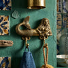 Solid brass mermaid double wall hook mounted on a turquoise coastal bathroom wall with hanging towel and natural sponge. Nautical beach house decor perfect for coastal bathrooms, spa-inspired interiors, mermaid decor, ocean-themed homes, and seaside cottage styling.