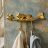 Brass mermaid wall hook with 3 hooks mounted near a mirror, holding towels as coastal wall hook set decor.